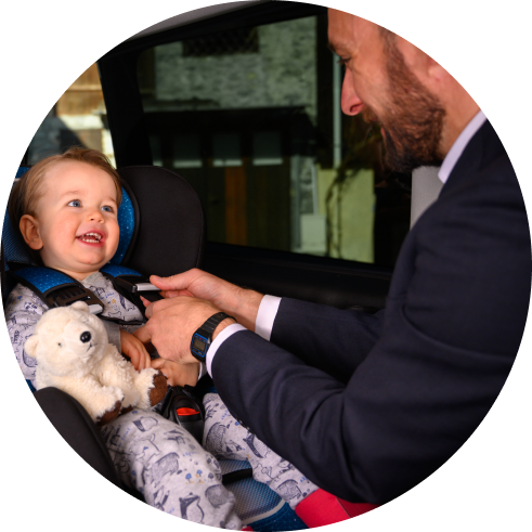 Smiling baby in car seat with adult in suit putting them in.